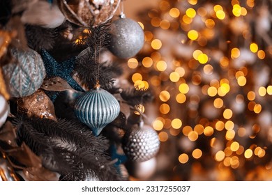 Close up view luxury fir branches decorated shiny silver, blue, white bauble or ball, xmas ornament. Blurred garland's lights, bokeh effect. Christmas holidays background. Festive new 2024 year.