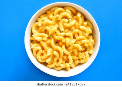 Close up view of macaroni and cheese in bowl over blue background. Top view, flat lay - Powered by Shutterstock