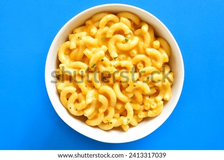 Close up view of macaroni and cheese in bowl over blue background. Top view, flat lay