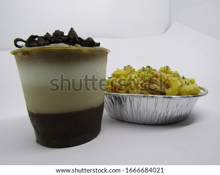 Close up view of macaroni schotel mac n cheese with elbow macaroni pasta cheesy cream, sausage beef meat cornet with a cup glass dessert of cold sweet  pudding chocolate milky white vanilla brown  Foto stock © 