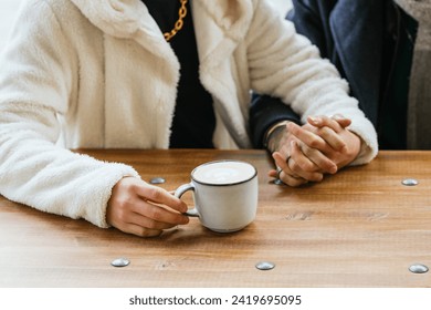 Close up view of a male couple holding hands while drinking coffee at a cafe. - Powered by Shutterstock