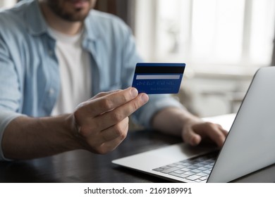 Close up view male hand holding credit card using laptop make on-line payments via e-bank application, do remote e-shopping at home. Secure e-payment, e-commerce client, instant money transfer concept Foto Stock