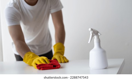 Close up view of man cleaning white wooden table using clothes and cleaning solution liquid spray. - Powered by Shutterstock