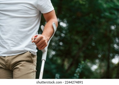 Close up view. Man with crutches is in the park outdoors. Having leg injury. - Shutterstock ID 2244274891