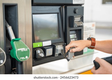 Close up view of man hand pays for fuel with a credit card on terminal of self-service filling station in Europe. High quality photo