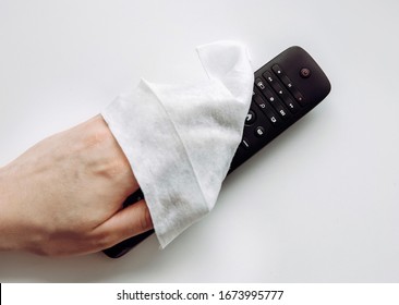 Close up view of man hand using antibacterial wet wipe for disinfecting home TV remote control.