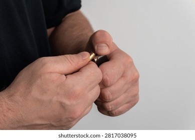 Close up view of man hands loading brass non lethal cartridge with black rubber bullet into handgun magazine on plain background.