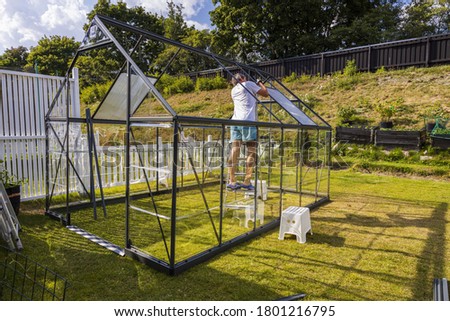 Close up view of man on back yard building green house. Gardening concept background.