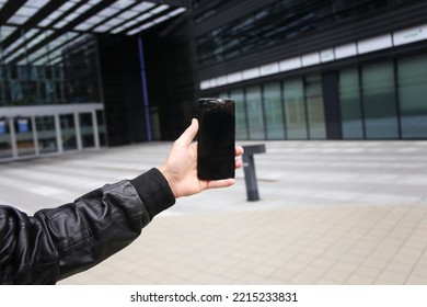 Close Up View Of Man Picking Up Broken Phone On Paved Sidewalk Outdoors