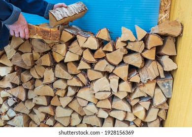 Close up view of a man putting firewood in a woodpile.