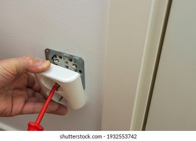Close up view of man repairing white light switch.  Electricity concept. Sweden.