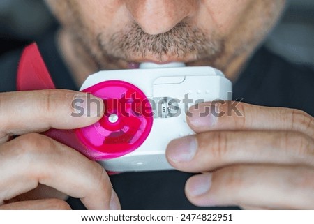 Close up view of man using medicine dry powder inhaler for treatment asthma or COPD diseases. Pharmaceutical product is used to treat lung inflammation and prevent asthma attack. High quality photo