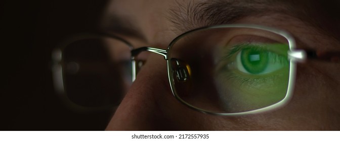 Close Up View Of Man Wears Computer Glasses For Reducing Eye Strain Blurred Vision Looking At Pc Screen With Computer Reflection Using Internet, Reading, Watching, Working Online.