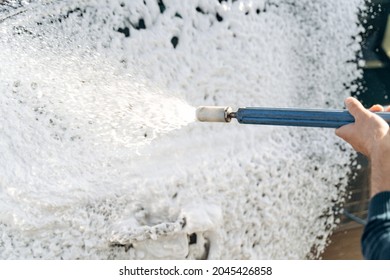 Close Up View Of The Man Worker Or Car Owner Washing Luxury Car On A Car Wash. Manual Car Washing Cleaning With Water At Service Station 