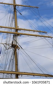 Close up view of masts and ropes of an ancient vessel with a blue cloudy sky in background. Abstract top boat image with horizontal and vertical lines. Vintage design of part of an old wooden ship.