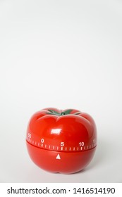 Close up view of mechanical tomato shaped kitchen clock timer for cooking and studying. Used for pomodoro technique for time & productivity management. Isolated on white background, set at 5 minutes.