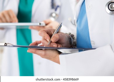 Close Up View Of Medical Doctor Hands Making Some Notes On Clipboard And Tablet. Health Care, Medical Service Or Education And Teamwork Concept.