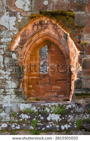 Close view of a medieval stone arch window framed by weathered masonry in historic abbey ruins.