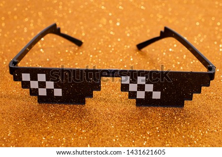 Close up view of meme pixel glasses isolated on a golden background.