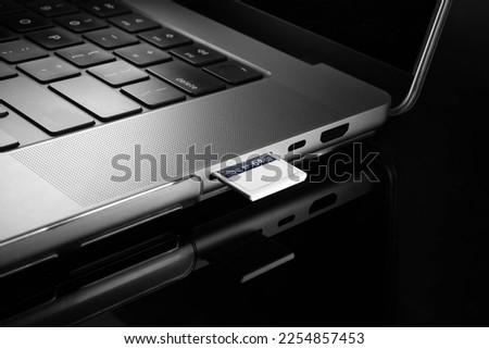 Close up view of a memory card inserted into a card reading slot of a laptop computer.