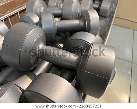 Close up view of messy stack of plastic dumbbells with various weights being displayed in a store.