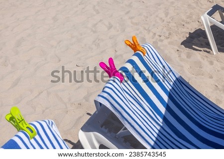 Close up view of Miami's sandy beach with sun loungers topped with beach towels and secured by clips. USA.