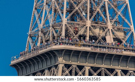 Close up view of middle section of the Eiffel Tower with tourists on observation deck timelapse in Paris, France. Sunny summer day with blue clody sky