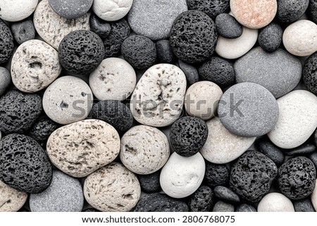 Close up view of mixed black volcanic lava stones and smooth white pebbles background