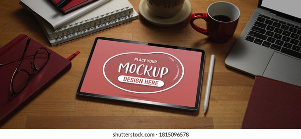 Close up view of mock up digital tablet on wooden worktable with laptop and supplies