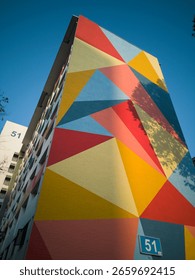 Close up view of modern colourful triangular design on a tall residential housing block in an old Singapore HDB public housing estate