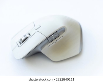 A close up view of a modern ergonomic wireless computer mouse resting on a clean white surface