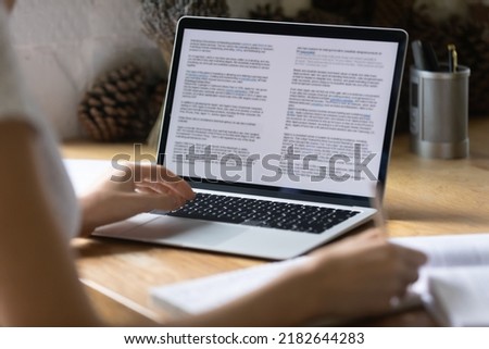 Close up view of modern technology digital gadget opened computer with electronic documents on screen. Young woman preparing report or reading scientific article, studying at home, education concept.