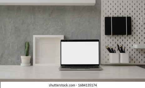 Nahaufnahme des modernen Arbeitsbereichs mit einem leeren Bildschirm-Laptop, Dekoration und Kopienraum auf dem Marmorschreibtisch mit Schreibtisch auf dem Regal mit Loft-Wand 