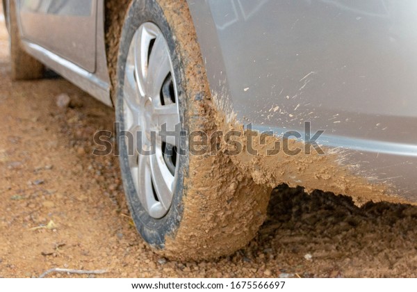 a close up view of mud sprayed all around a car tyre and\
back bumper 