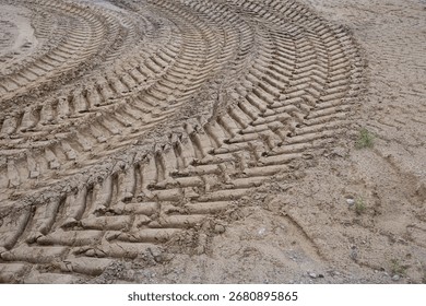 Close up view of muddy ground with multiple tractor tire marks forming repeating lines and curves