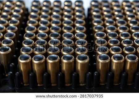 Close up view of multiple non lethal handgun cartridges with black rubber bullets arranged in plastic organizer tray.