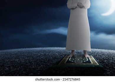 Close Up View Of A Muslim Man In A Praying Position (salat) On A Prayer Rug With A Night Scene Background