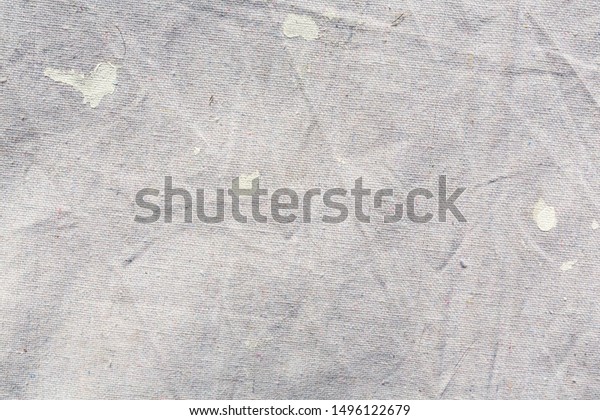 Close view of a muslin drop cloth with off\
white paint spills and\
splotches.