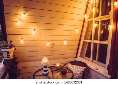 Close Up View Of Nautical Theme Home Balcony At Night With String Light Bulbs.