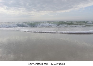 A close up view of ocean waves rolling on the shore. Beautiful foamy waves washing up on a sandy beach. 