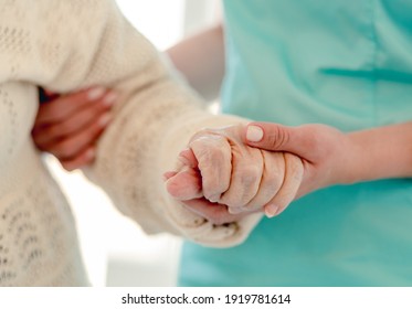 Close up view of old woman leaning on nurse while walking