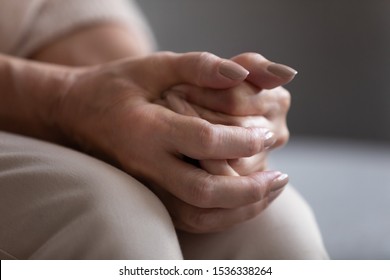 Close up view of older senior female hands clasped, elderly mature woman grandmother praying with hope concerned worried about health care arthritis problem and loneliness poverty depression concept