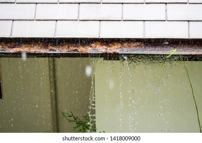 Close Up View On Clogged Rain Gutter In The Rain. Home Guttering, Gutters