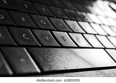 a close up view on a computer keyboard illuminated by a white light. (black and white photography)