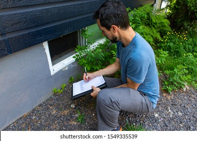A close up view on environmental home quality inspector at work, filling in a form as he inspects the exterior of a cellar window, with room for copy. - Shutterstock ID 1549335539