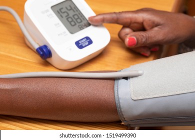 A Close Up View On The Forearm Of An African Woman As She Takes The Readings From A Blood Pressure Monitor, The Reading Falls Just Above The Healthy Range, Suggesting Hypertension.