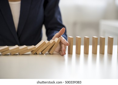 Close up view on hand of business woman stopping falling blocks on table for concept about taking responsibility. - Shutterstock ID 500339383