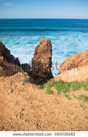 close up view on huge cliff of bordeira beach by atlantic ocean with waves in blue sky, algarve, portugal