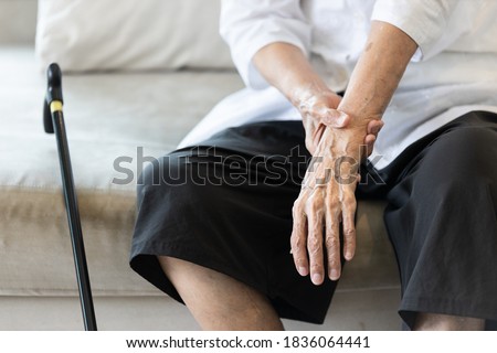 Close up view on the shaking hand of the senior woman,symptom of resting tremor or parkinson's disease,old elderly patient holding her wrist to control hand tremor,neurological disorders,brain problem