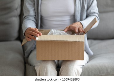 Close up view on woman lap is small carton box, female opening it and looks inside. Transport services, addressee recipient received parcel or client sending package, quick post mail delivery concept - Shutterstock ID 1569482893